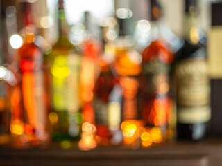 Beautiful bokeh from a row of alcoholic bottles in backlight. - obrazy, fototapety, plakaty