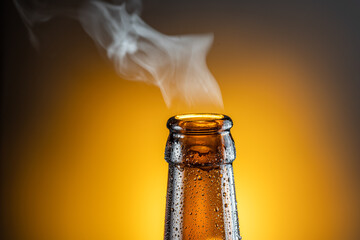 Opened bottle of cold beer and gas output isolated on a yellow background.