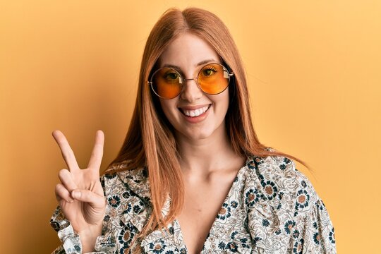 Young irish woman wearing bohemian and hippie style smiling with happy face winking at the camera doing victory sign. number two.