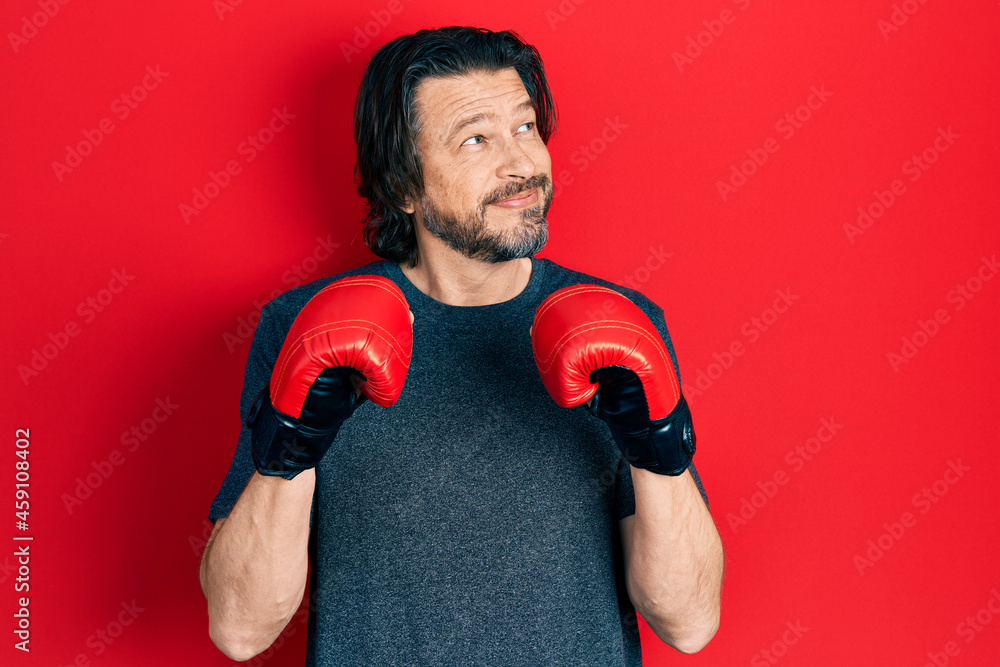 Sticker middle age caucasian man using boxing gloves smiling looking to the side and staring away thinking.