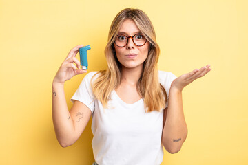 pretty blonde girl feeling puzzled and confused and doubting. asthma inhaler concept
