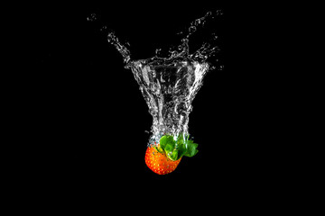 Strawberry splash in the water against black background