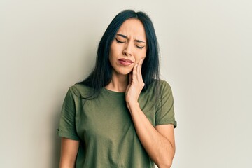 Fototapeta premium Young hispanic girl wearing casual t shirt touching mouth with hand with painful expression because of toothache or dental illness on teeth. dentist