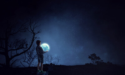 Boy holding moon at night