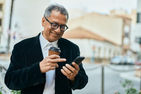 Middle age southeast asian man smiling using smartphone and drinking a cup of coffee at the city
