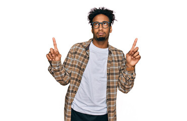 Young african american man with beard wearing casual clothes and glasses pointing up looking sad...