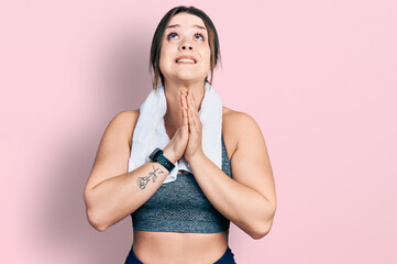 Young hispanic girl wearing sportswear and towel begging and praying with hands together with hope...