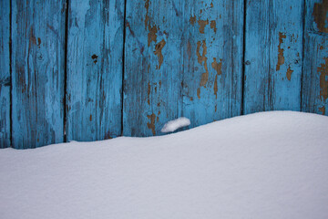blue wood texture background with untouched snow, peeling paint on wood in winter