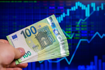 hundreds of euro banknotes on the background of a stock chart