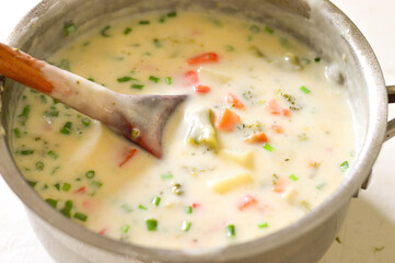 Cheese (creamy) soup in a saucepan with broccoli, carrots, herbs. Horizontal