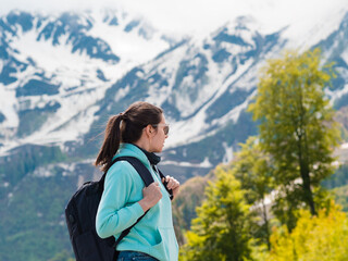 Young female tourist with a backpack on her back hiking in the mountains,