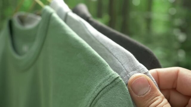 cotton t-shirts on hangers outdoor, clothes of various colors. sustainable fashion concept, eco fashion. textile and fashion industries, environmental problems, recycling, synthetic matherials