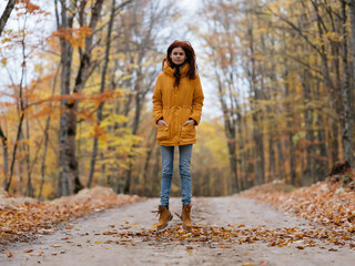 woman in yellow jacket in the forest road journey autumn leaves