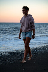 Fototapeta na wymiar Sad woman walks along the beach with dramatic cold waves