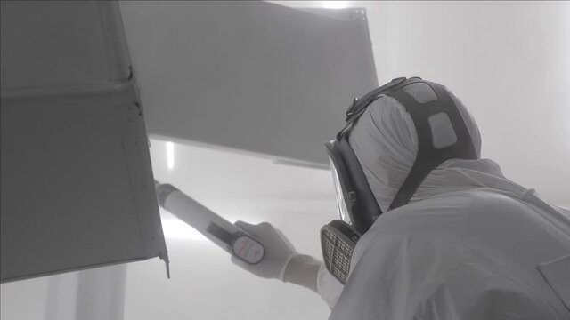 Industrial painting metal powder coating paint manufacturing process. Powder coating of metal products. Coveralls worker with spray gun painting parts metal workshop. Metalwork workpiece factory paint