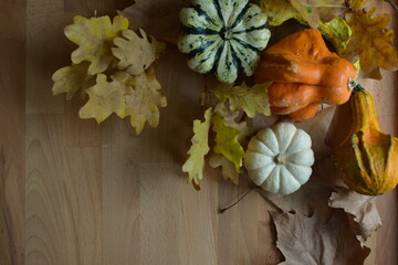 Decorative pumpkins: autumn leaves on wooden background 01