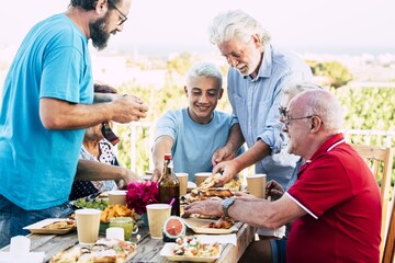 Multi generation family enjoying food and drinks party outdoors during summer holiday. Happy family spending leisure time having food at outdoors table setting