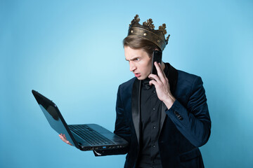businessman with a crown on his head uses a laptop and a phone.
