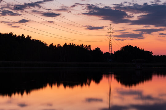 Electric power lines during the sunset reflected in water in Helsinki Finland near Pikku Huopalahti