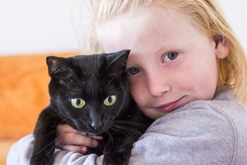 Close up of little boy playing with kitten in living room at home. Portrait of boy with young cat. Cute little boy with pet cat staring at home. Loving and caring pet animal