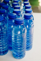 Several lined up drinking bottled water with no label on white table. Selective focus.