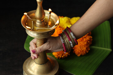Indian woman holding ighted oil lamp Onam Diwali vishu celebration Indian festival decorating...
