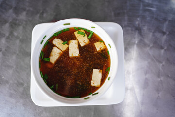 soup with shrimp, algae, mushrooms and tofu cheese in a white plate. top view.