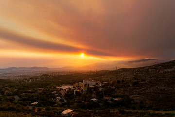 Fototapeta premium Athens view at sunset with red and yellow clouds from Penteli mountain.