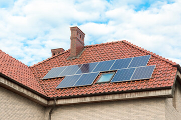 Fototapeta premium Solar panels on the tiled roof of the building. House roof covered with solar panels. Alternative electricity source - Sustainable Resources Concept