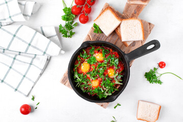 Shakshouka with quail eggs and tomato sauce topped with herbs served in cast iron pan. Middle Eastern and African meal. Top view