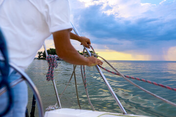sailor on yacht pulls rope in stormy weather in sea. shallow depth of field photo
