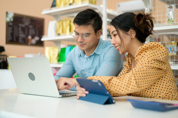 Business owners are analyzing business data , talking and smiling in modern shop