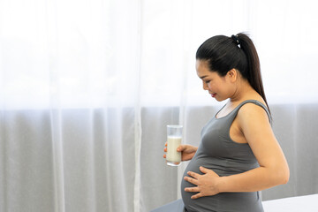 Pregnant woman drinking milk with high calcium for baby. Healthy nutrition during pregnancy concept.