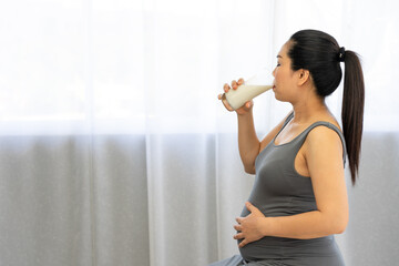 Pregnant woman drinking milk with high calcium for baby. Healthy nutrition during pregnancy concept.