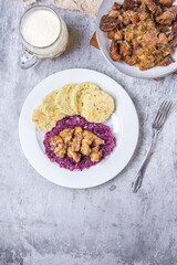 Roast pork with dumplings and sauerkraut. Typical Czech national dish with homemade bread dumplings red cabbage and beer on stone background. Top view. Vertical photo.