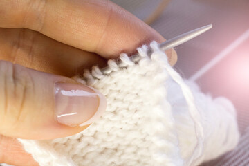 Women's fingers and loops on knitting needles, knitting hobby
