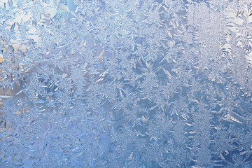 Winter light white and blue background or wallpaper. Drawing of crystals of ice and frost on the window pane. Abstract Christmas and New Year backdrop