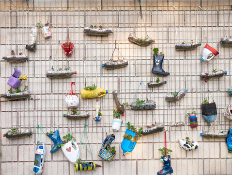 Wall filled with flowerpots made with plastic bottles, outdoors, made by schoolchildren - Powered by Adobe