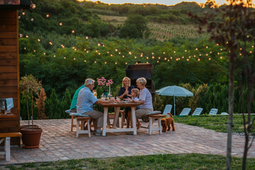 Cheerful family enjoying a family dinner outside at home during evening