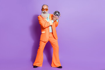 Full size photo of old funky happy man wear sunglass hold hand disco ball club isolated on purple...