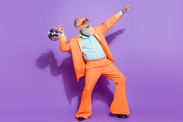 Full length photo of old positive happy man hold disco ball point look empty space isolated on...