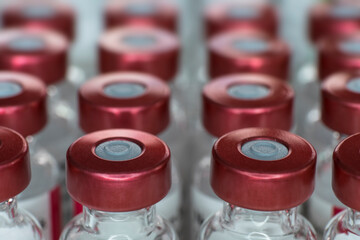 Close-up of Glass medicine or vaccine bottles with injection fluid with red aluminium caps. Narrow...