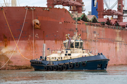 Southampton, England, UK. 2021.  Tug manoeuvres a bulk carrier ship towards her berth in the port of Southampton.