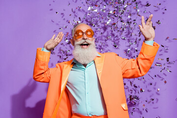 Photo of cheerful joyful cool old man confetti fall wear sunglass clubber isolated on purple color...