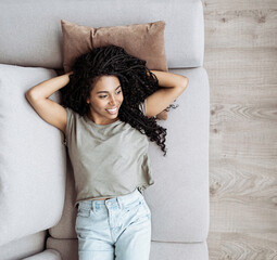 Young woman relaxing at home lying on sofa. African american girl resting in her room. Enjoy life,...