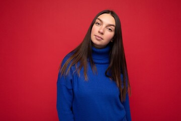 Fototapeta premium Young self-confident beautiful brunette woman with sincere emotions isolated on background wall with copy space wearing casual trendy blue sweater looking at camera
