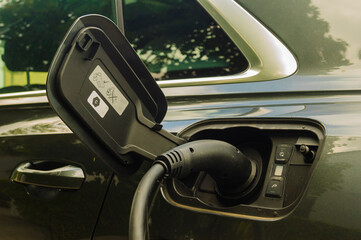 Electric car charging battery at a charger station - close-up of a charging plug in the car