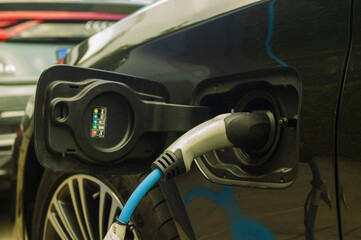 Electric car charging battery at a charger station - close-up of a charging plug in the car