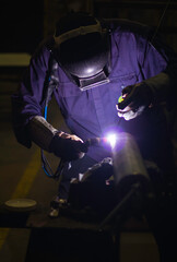 Skillful welders weld steel in the factory. Construction site metal welder. builder wear fireproof gloves for safety at work.