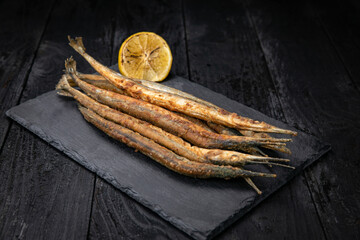 fried fish with lemon on a dark table
